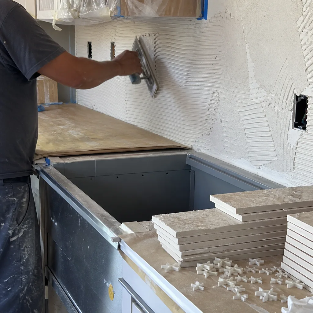 Contractor applying mortar to kitchen wall for tile installation